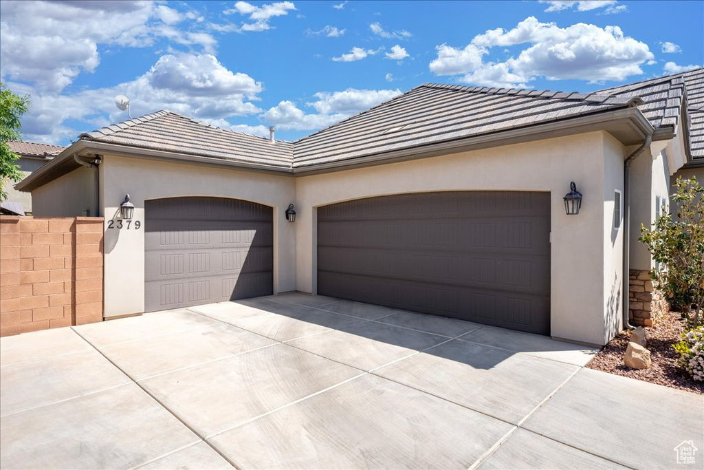 Single story home featuring an attached garage, driveway, a tile roof, and stucco siding