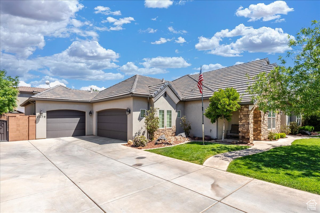 Single story home with a garage, a front yard, stucco siding, driveway, and a tile roof