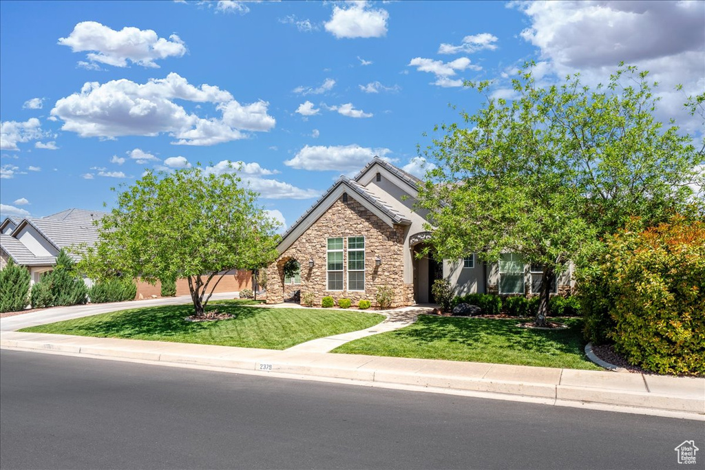 Obstructed view of property featuring a front yard, stucco siding, a tiled roof, and stone siding