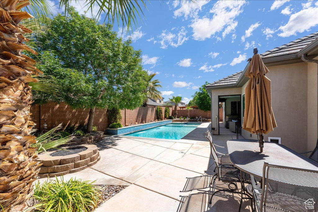 View of swimming pool featuring a fenced in pool, a fenced backyard, a patio area, and an outdoor fire pit