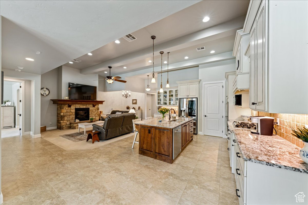 Kitchen featuring a sink, light stone countertops, backsplash, and open floor plan