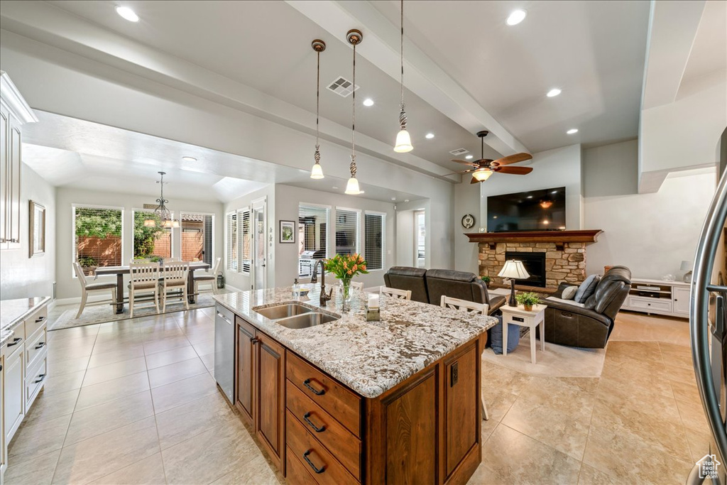 Kitchen with a ceiling fan, appliances with stainless steel finishes, brown cabinets, a sink, and light tile patterned flooring