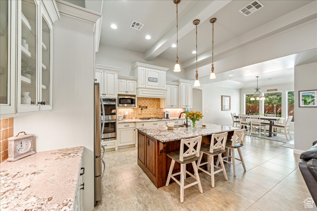 Kitchen featuring stainless steel appliances, visible vents, a breakfast bar, and tasteful backsplash