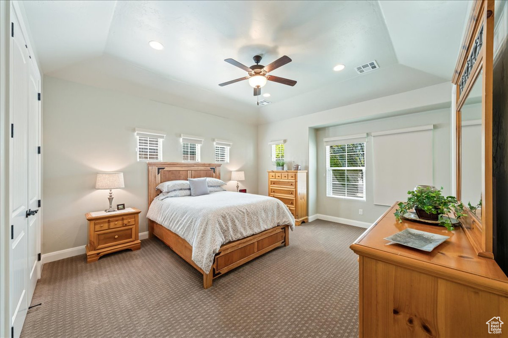 Bedroom featuring visible vents, baseboards, a tray ceiling, and light colored carpet