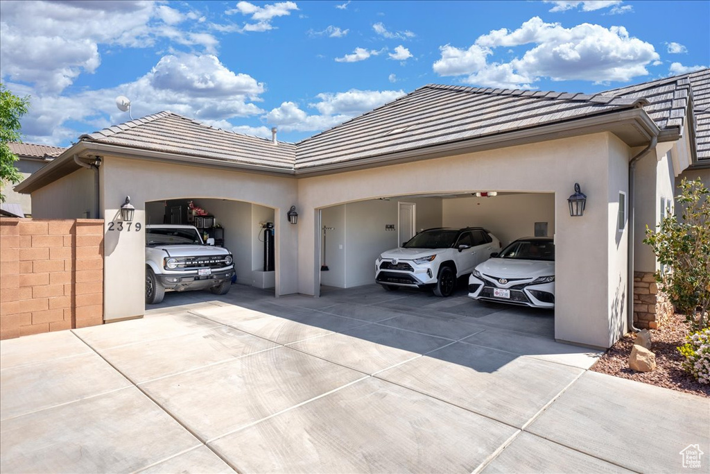 View of front of house featuring an attached garage, stucco siding, driveway, and a tiled roof
