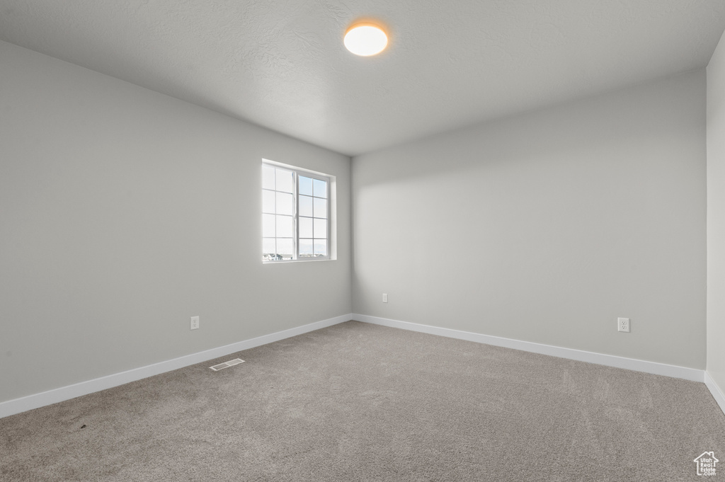 Carpeted spare room featuring baseboards