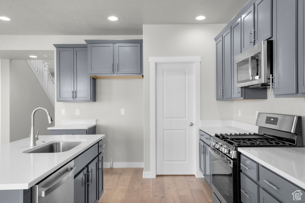 Kitchen featuring stainless steel appliances, a sink, light wood-style floors, light countertops, and recessed lighting