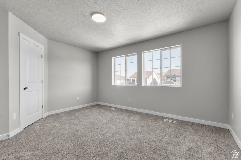 Carpeted spare room with a textured ceiling and baseboards