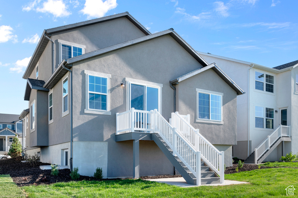 Rear view of house featuring stairs, stucco siding, and a yard