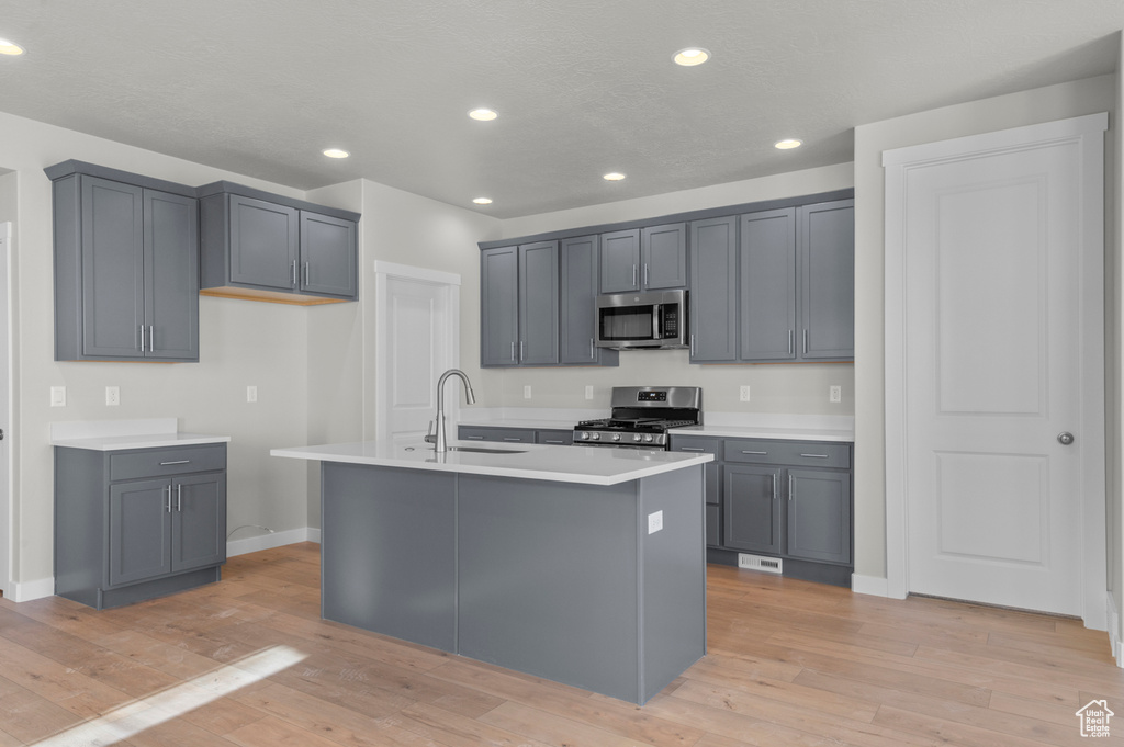 Kitchen featuring stainless steel appliances, baseboards, a sink, light wood-style flooring, and recessed lighting