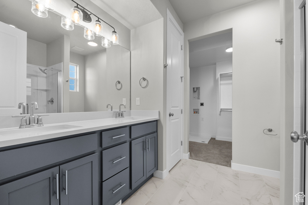 Full bath featuring double vanity, marble finish floors, a shower with door, and baseboards