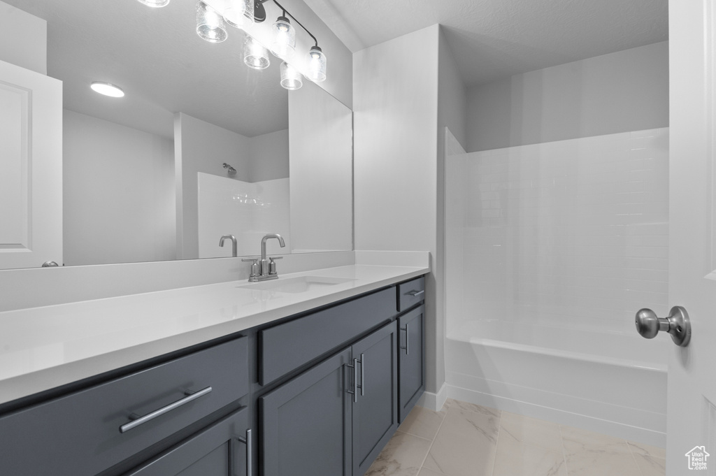 Full bath with vanity, marble look tile flooring, and bathtub / shower combination