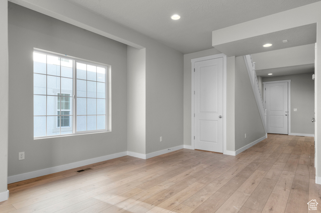 Empty room featuring baseboards, light wood-style flooring, and recessed lighting