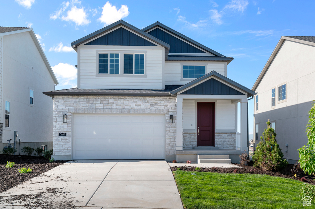 Craftsman inspired home with board and batten siding, driveway, stone siding, and a garage