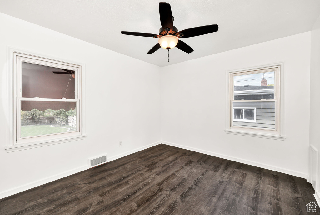 Spare room with baseboards, a ceiling fan, dark wood-type flooring, and visible vents