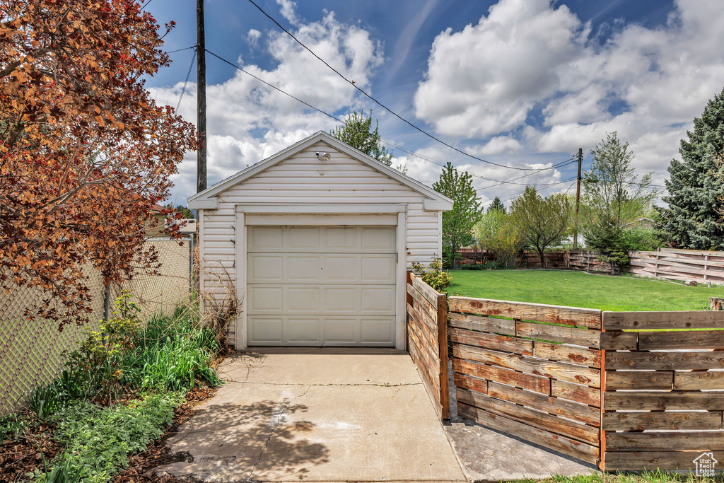 Detached garage featuring fence and concrete driveway