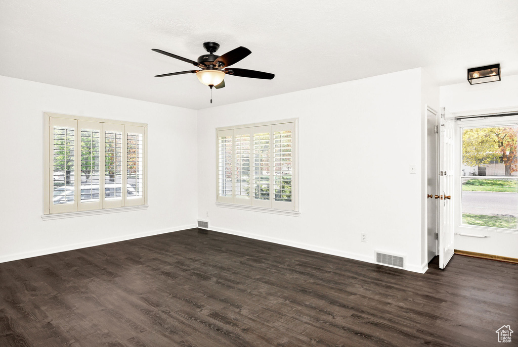 Empty room with baseboards, ceiling fan, dark wood finished floors, and visible vents