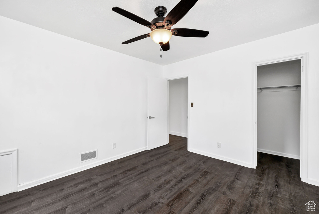 Unfurnished bedroom with visible vents, a closet, dark wood-style flooring, baseboards, and a spacious closet