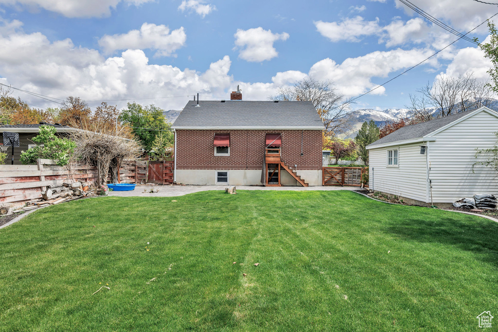 Rear view of house featuring a fenced backyard, a chimney, a yard, and brick siding