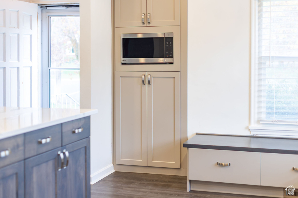 Kitchen with stainless steel microwave, visible vents, dark wood-style floors, and a wealth of natural light