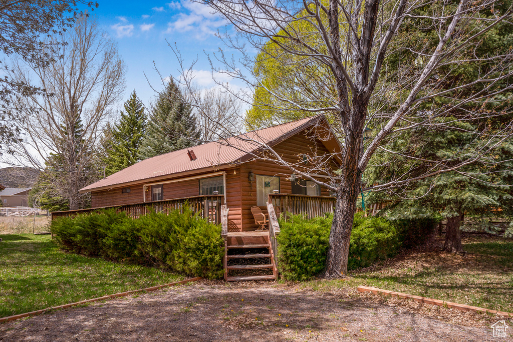 View of front of house with a front lawn, a wooden deck, and metal roof