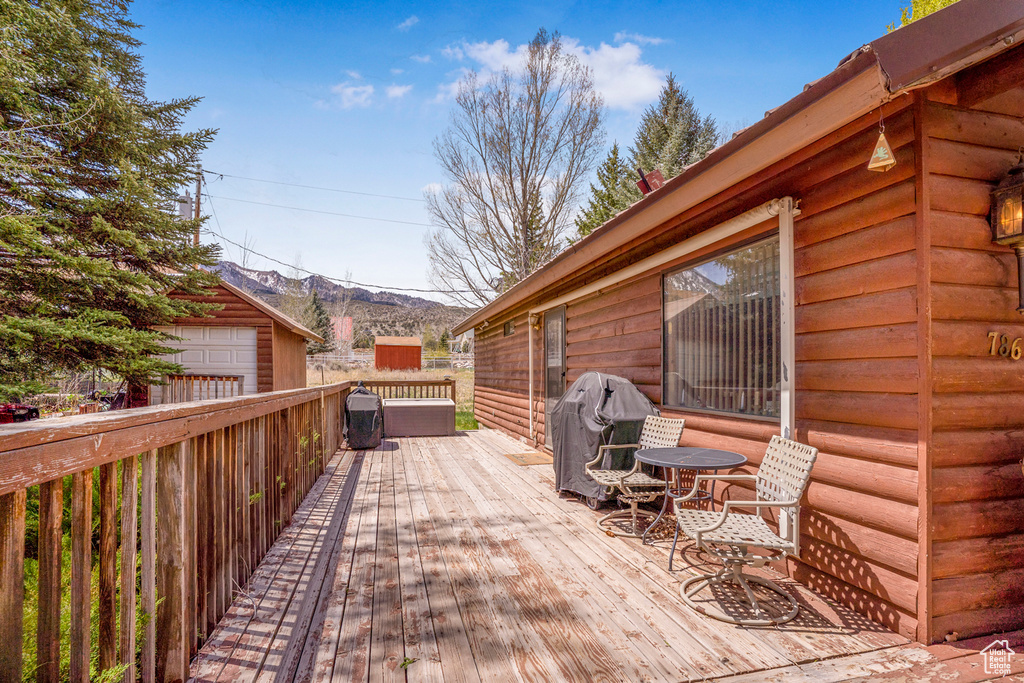 Deck featuring an outdoor structure, a garage, a mountain view, and grilling area