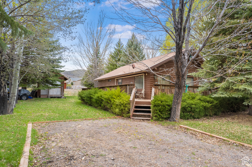 Exterior space featuring log exterior, a wooden deck, and a front lawn