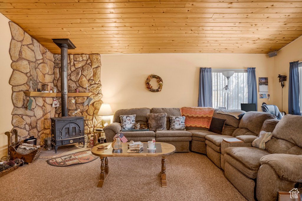 Living room featuring a wood stove, wood ceiling, and carpet flooring