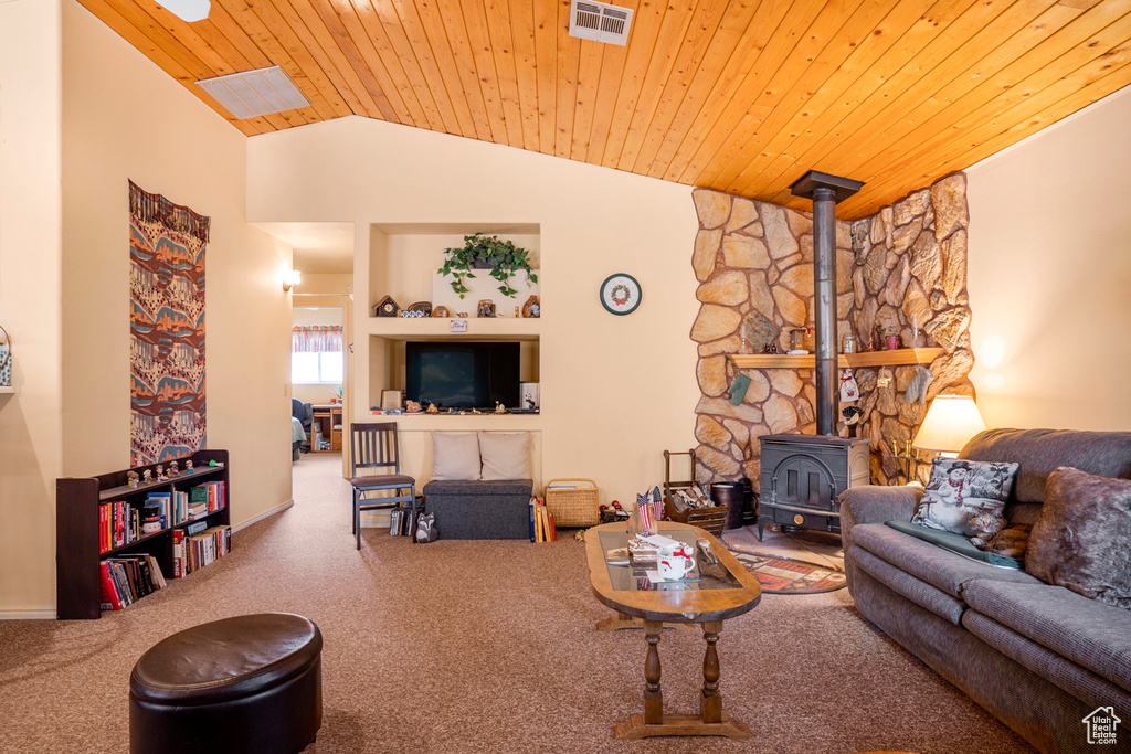 Carpeted living area featuring visible vents, a wood stove, baseboards, vaulted ceiling, and wood ceiling