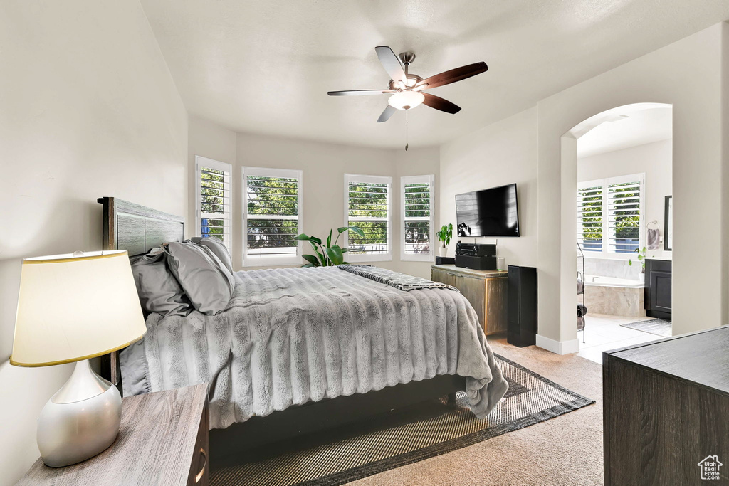 Bedroom with arched walkways, ensuite bath, multiple windows, and light carpet