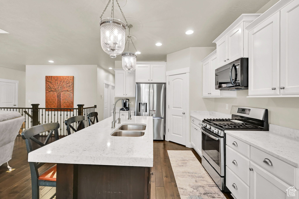 Kitchen featuring a sink, dark wood finished floors, a kitchen island with sink, and stainless steel appliances