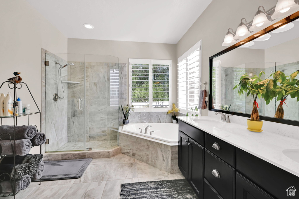 Full bath with a sink, double vanity, a shower stall, and a bath