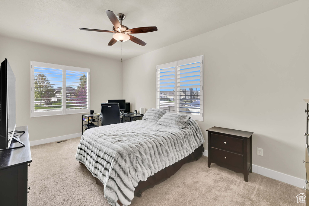 Bedroom featuring baseboards, a ceiling fan, and light carpet
