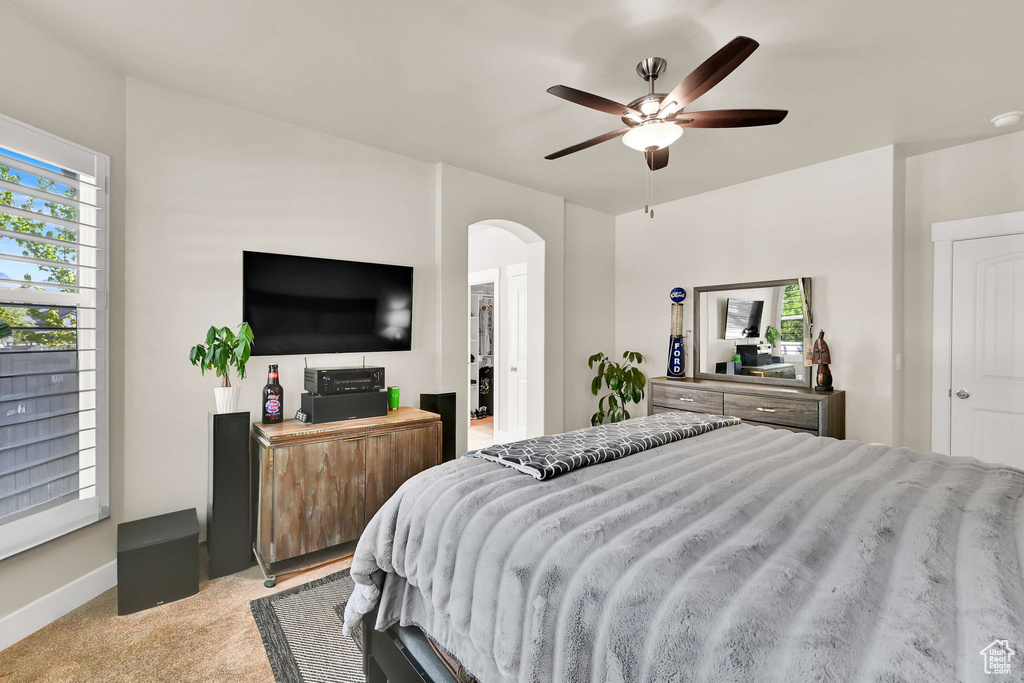 Bedroom featuring arched walkways, ceiling fan, and light carpet