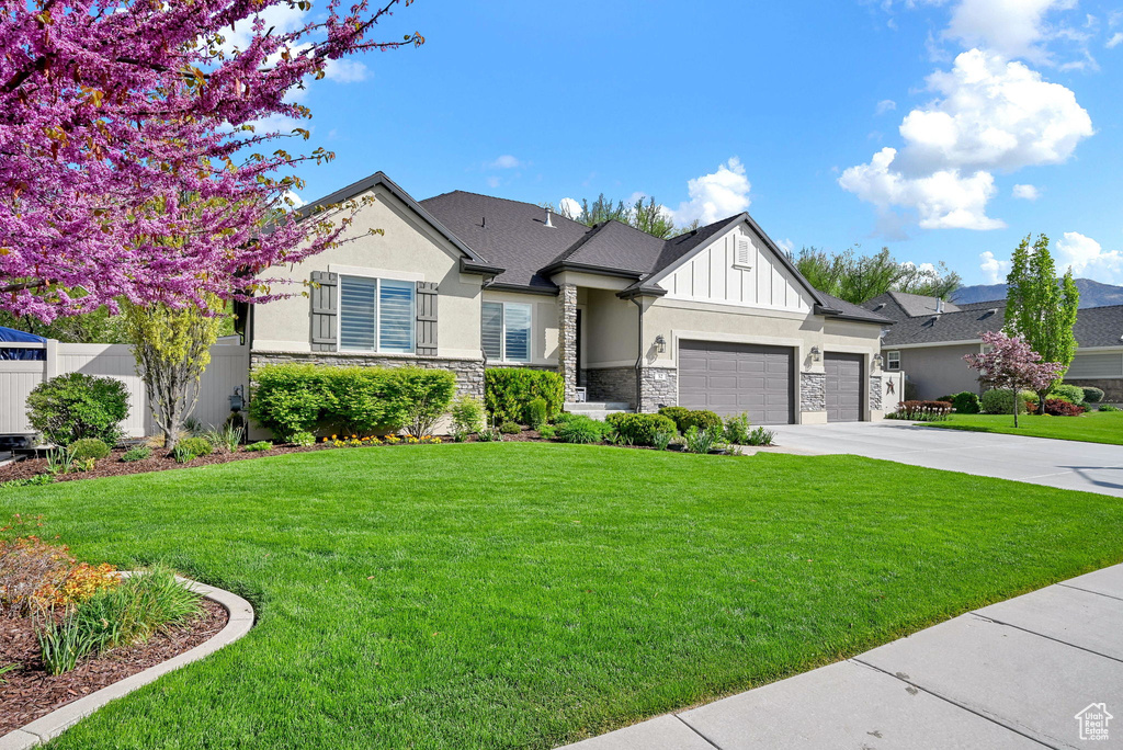 View of front facade with a garage, stucco siding, concrete driveway, and stone siding