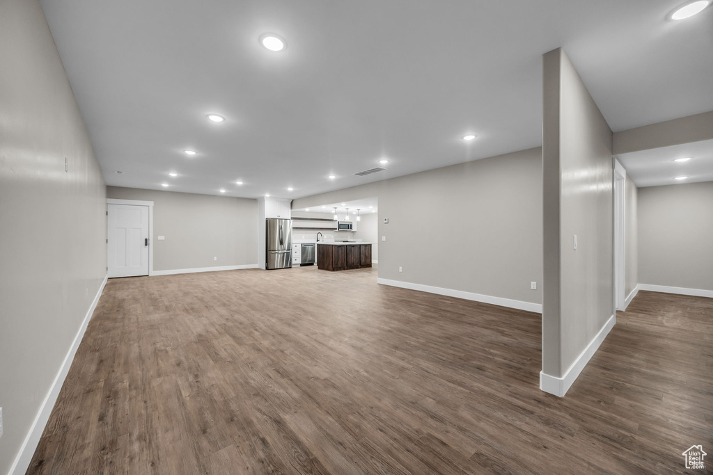 Unfurnished living room featuring dark wood-style flooring, baseboards, visible vents, and recessed lighting