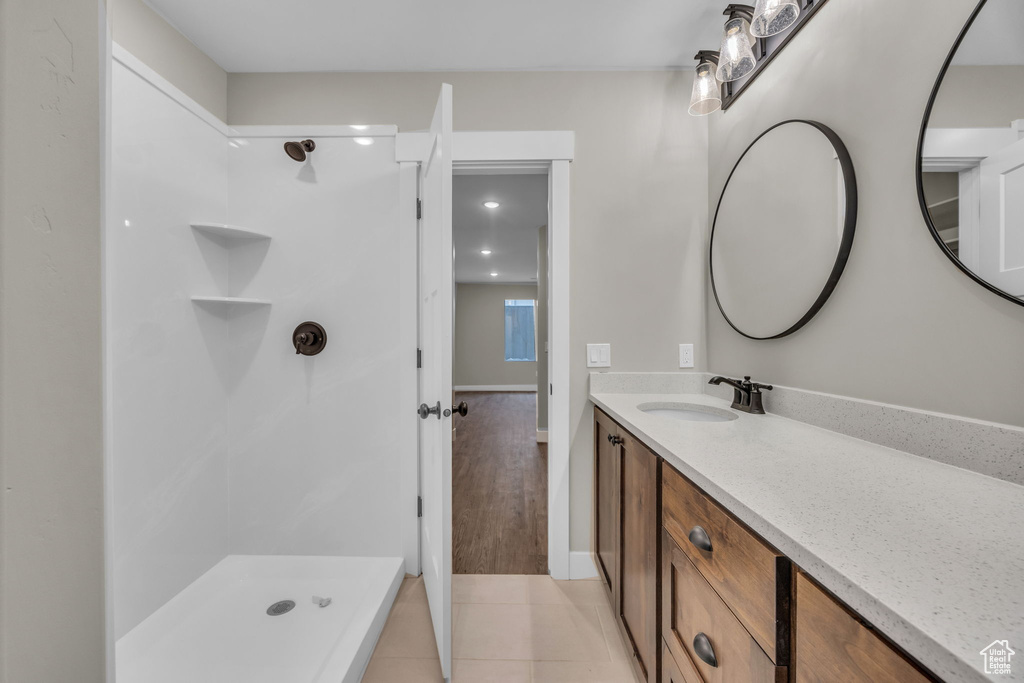 Bathroom featuring vanity, tile patterned floors, baseboards, and a shower
