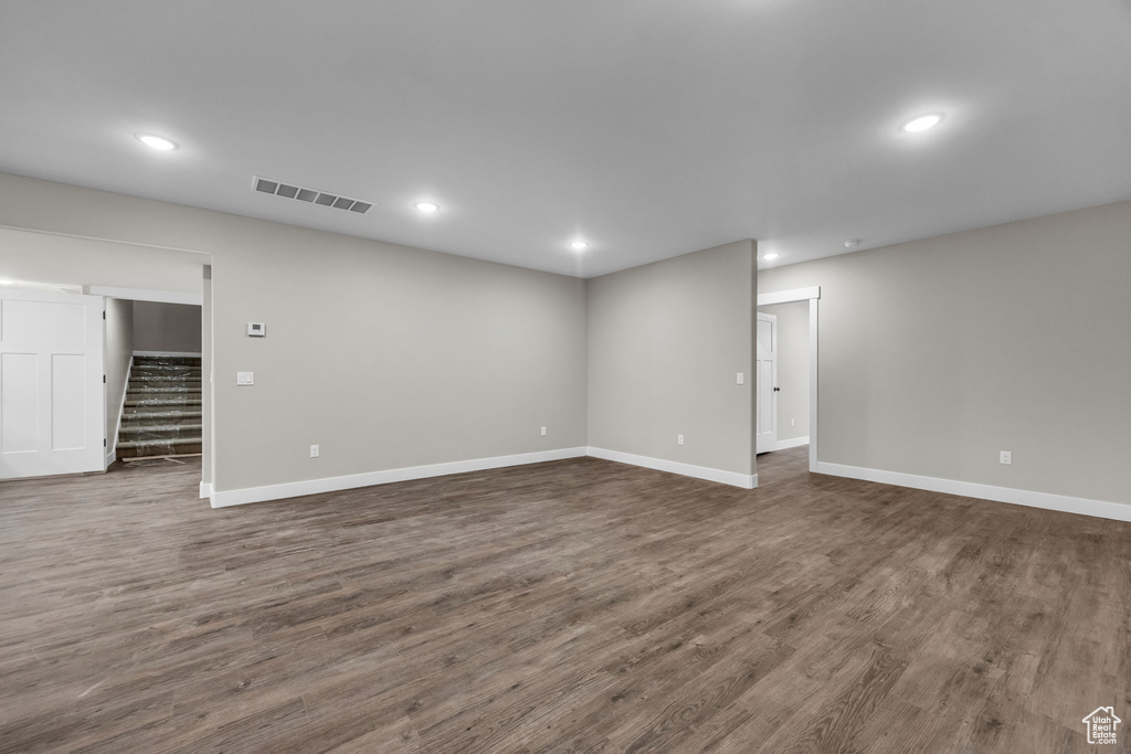 Below grade area featuring stairway, baseboards, dark wood-style floors, and visible vents