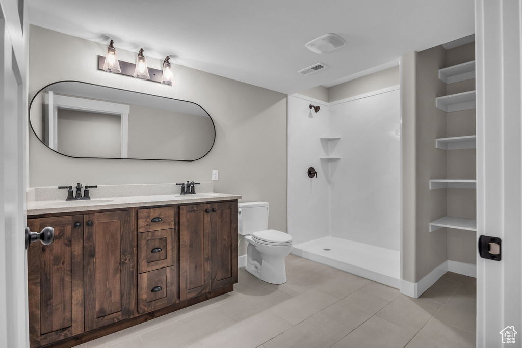 Bathroom with a sink, double vanity, toilet, a shower, and visible vents