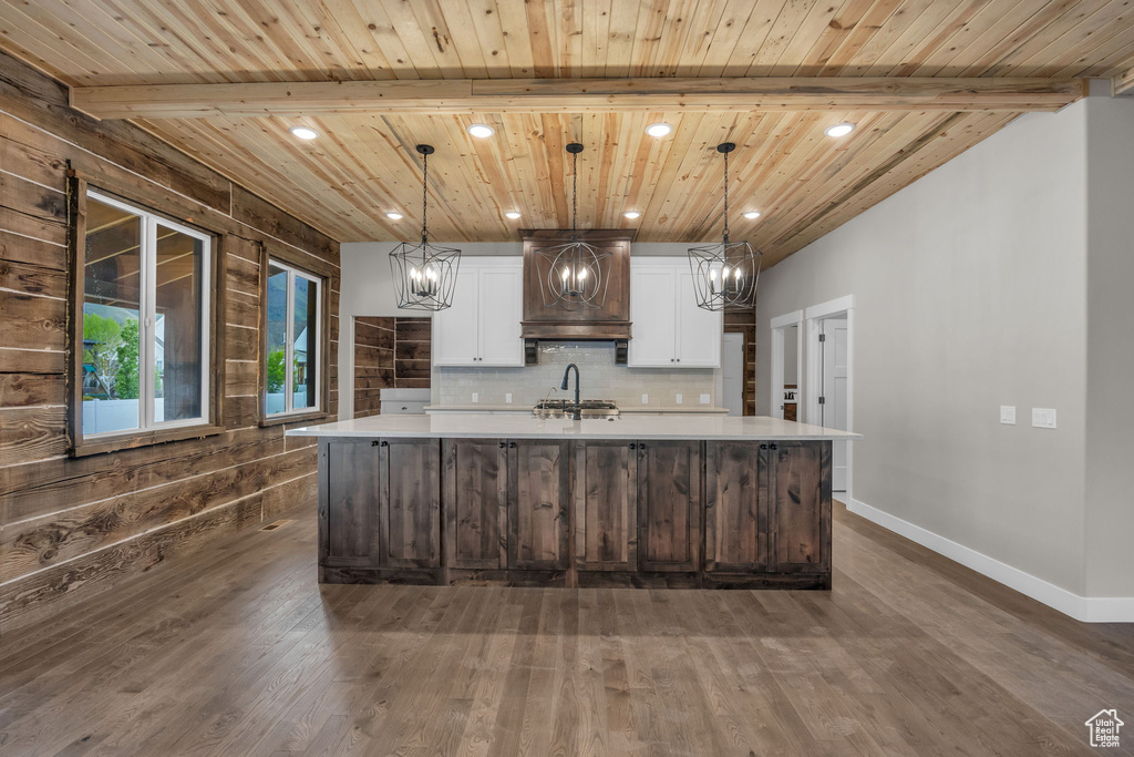 Kitchen with light countertops, an inviting chandelier, wooden ceiling, and premium range hood
