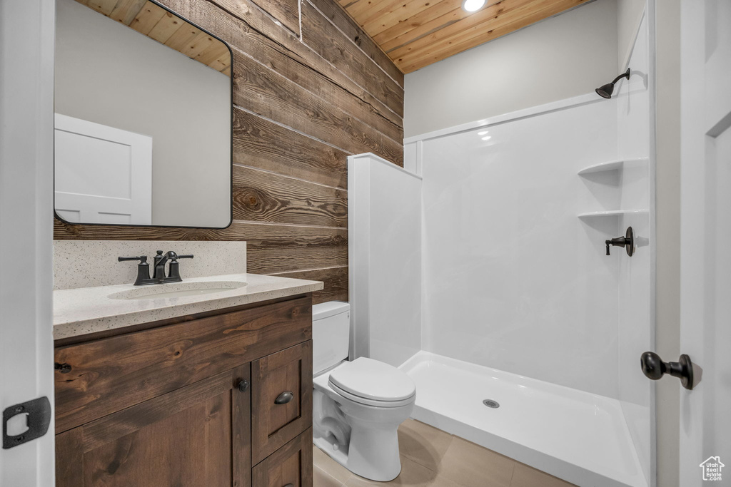 Full bath featuring wood ceiling, wood walls, a walk in shower, vanity, and toilet
