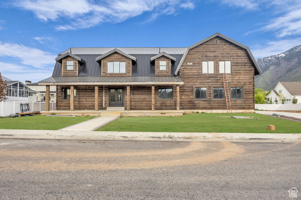 View of front of home featuring metal roof, a porch, and a front lawn