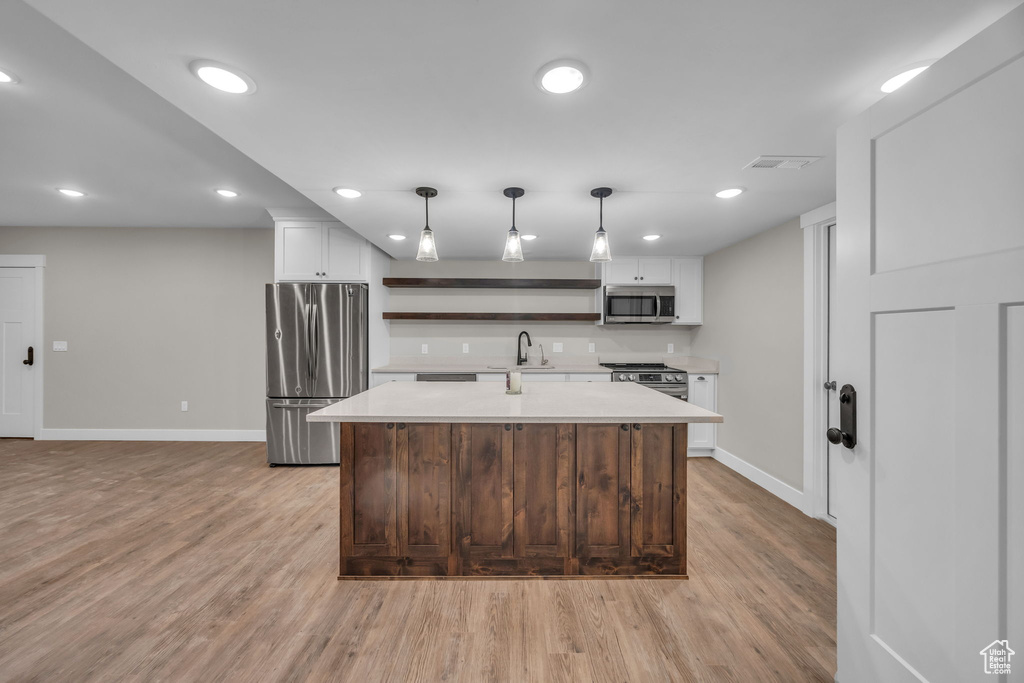 Kitchen featuring open shelves, baseboards, light countertops, a sink, and appliances with stainless steel finishes