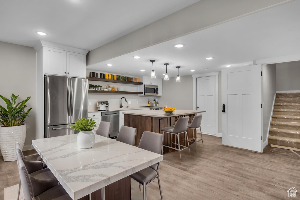 Dining space featuring recessed lighting, wet bar, stairway, and light wood-type flooring