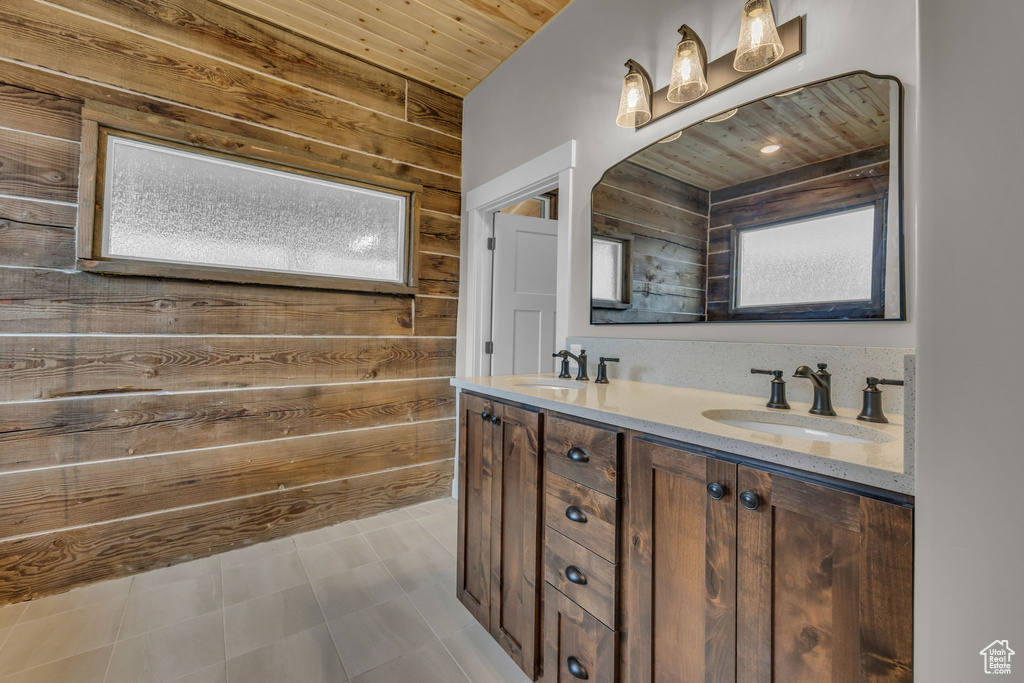 Full bath with wooden walls, double vanity, wooden ceiling, and a sink