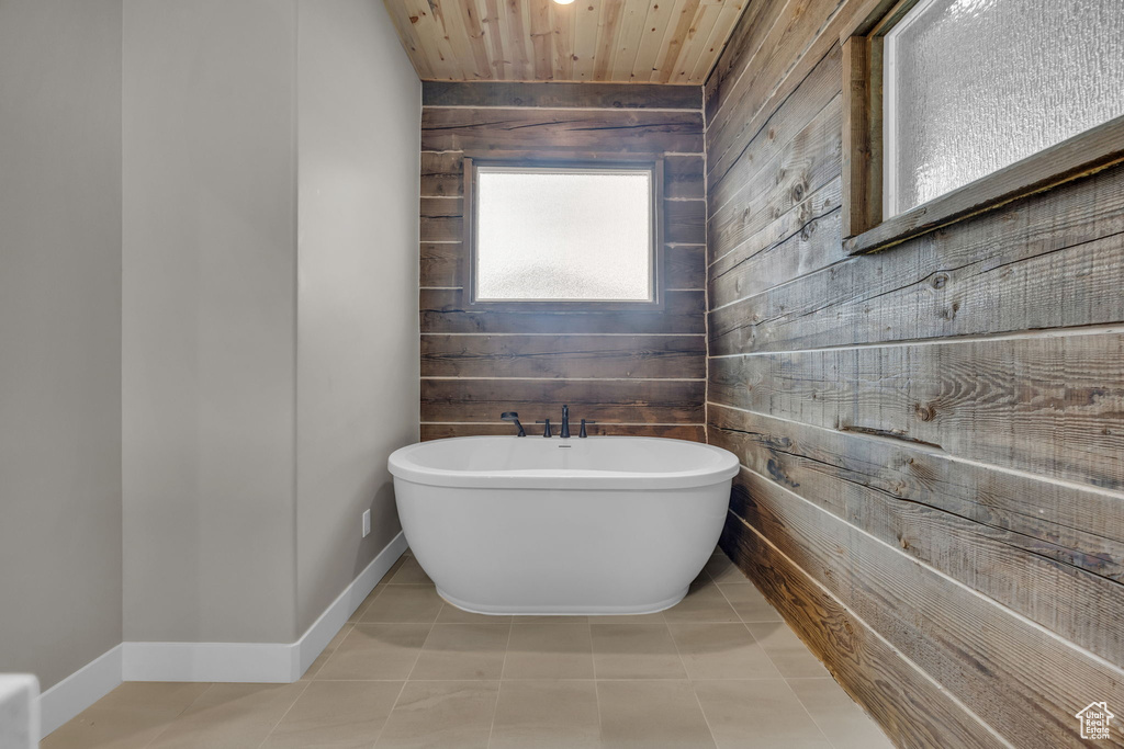 Bathroom featuring wooden ceiling, baseboards, a soaking tub, and wood walls