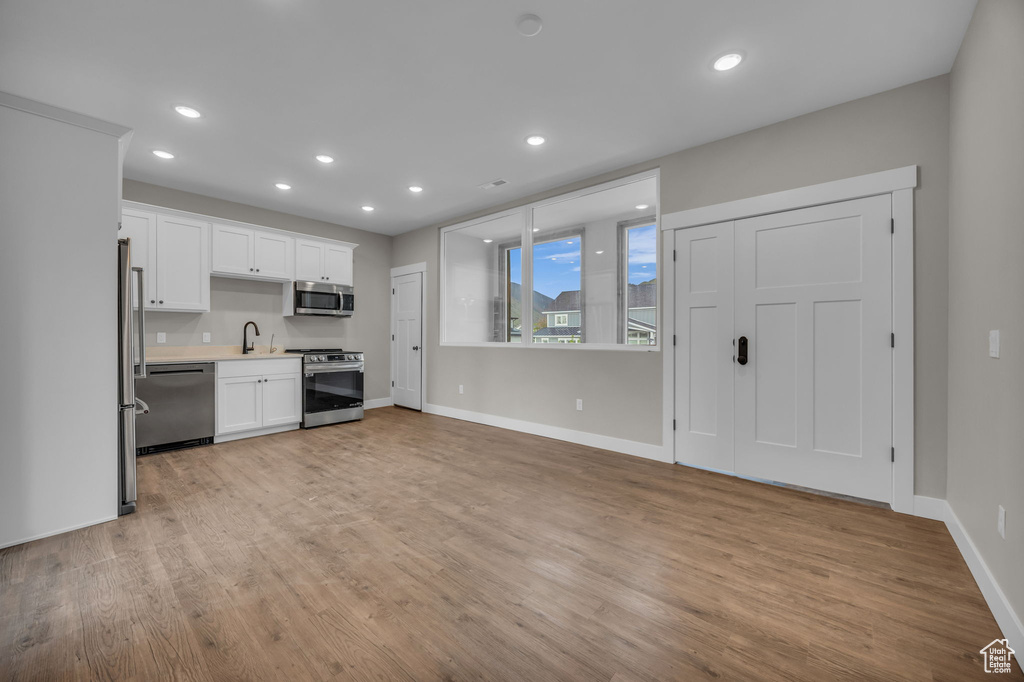 Kitchen featuring a sink, light countertops, baseboards, stainless steel appliances, and white cabinetry