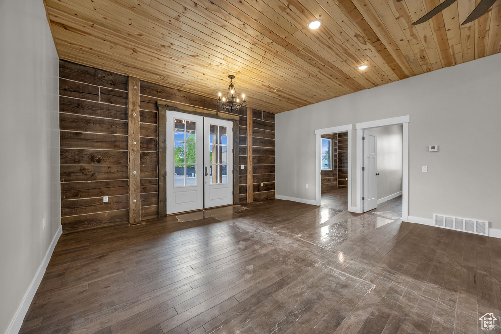 Spare room with wood ceiling, visible vents, wood finished floors, baseboards, and an inviting chandelier