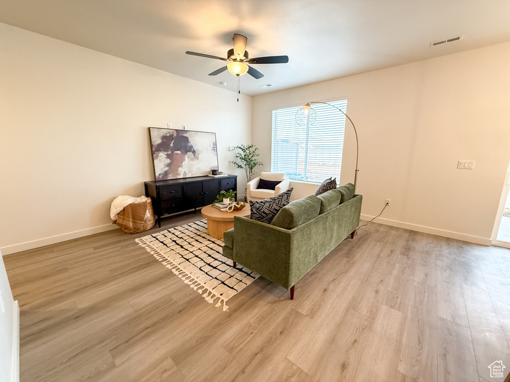 Living room with ceiling fan, visible vents, baseboards, and light wood-type flooring