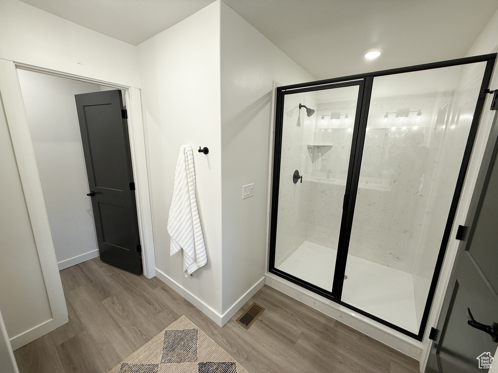 Full bath with baseboards, wood finished floors, visible vents, and a shower stall